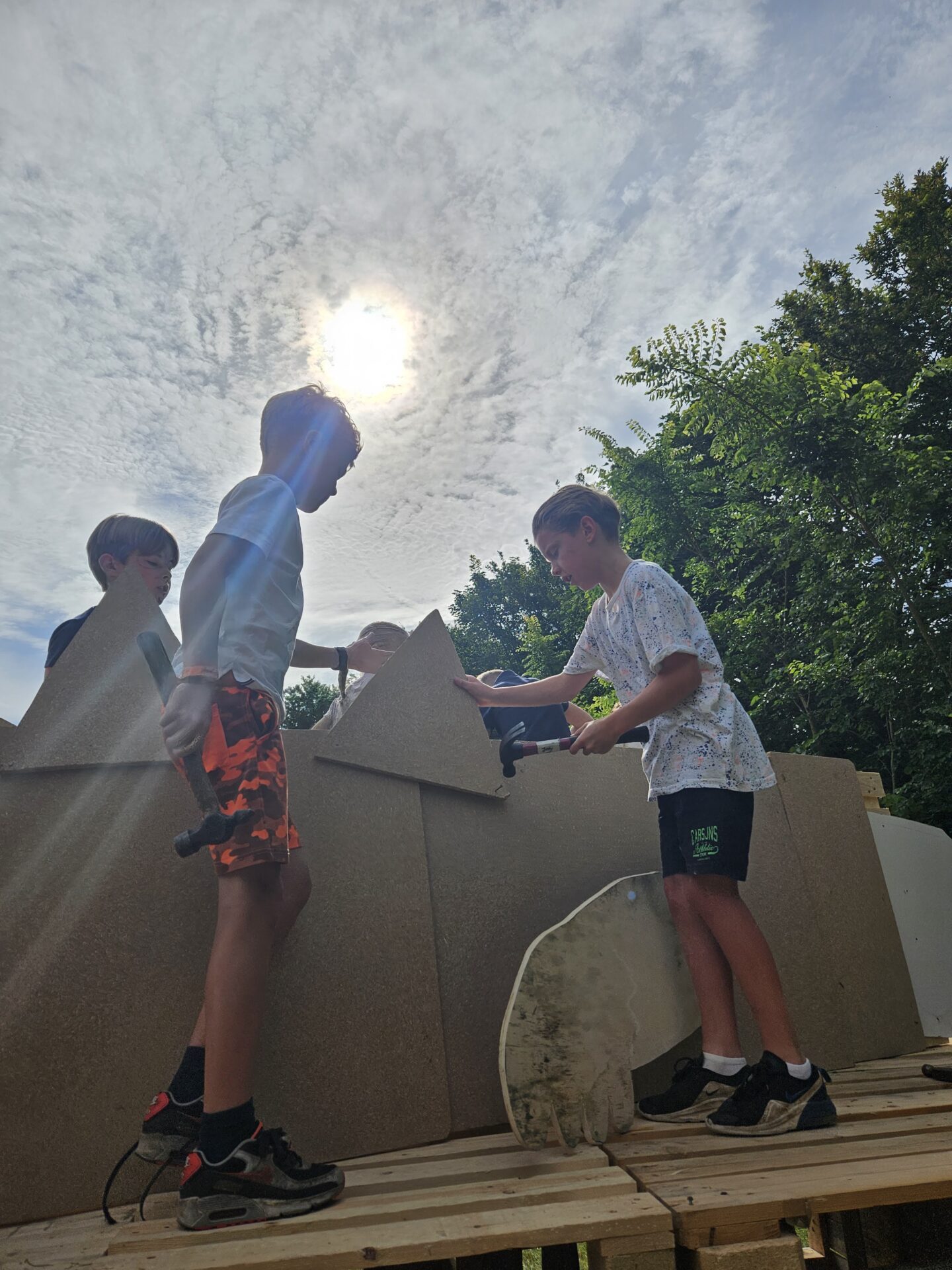 Vijf kinderen die op pallets staan en druk aan het bouwen zijn
