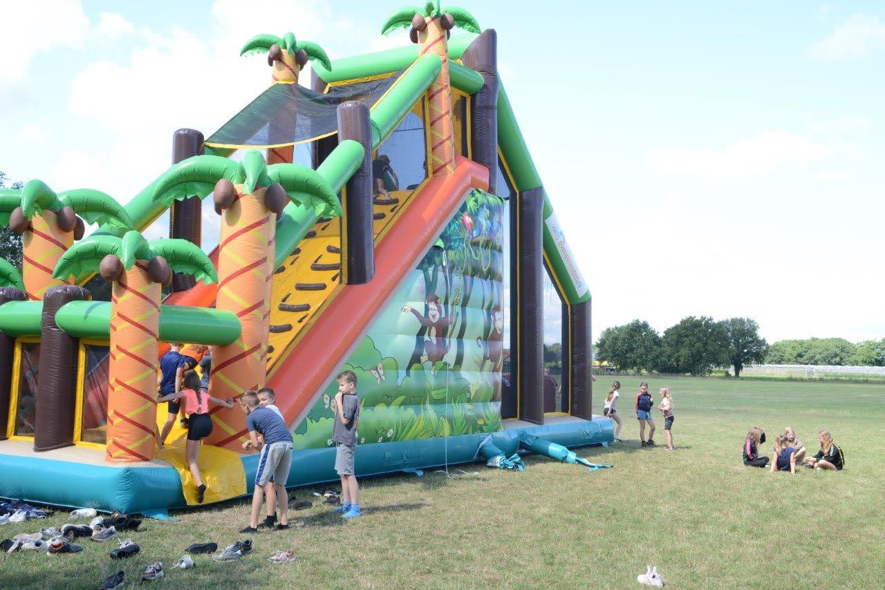 Kinderen bij springkussen waar op geklommen kan worden met veel schoenen op de grond